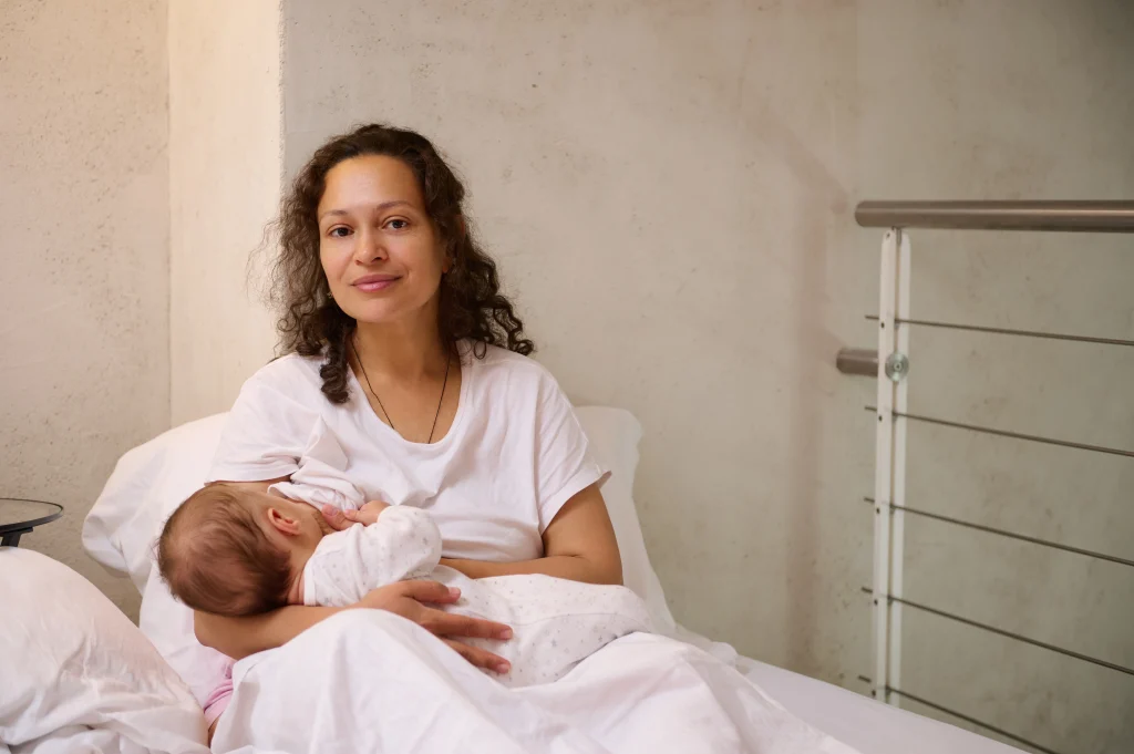 Mère allaitant son bébé dans un cadre paisible, illustrant le droit au congé d’allaitement en France et les besoins des jeunes mamans après la naissance.