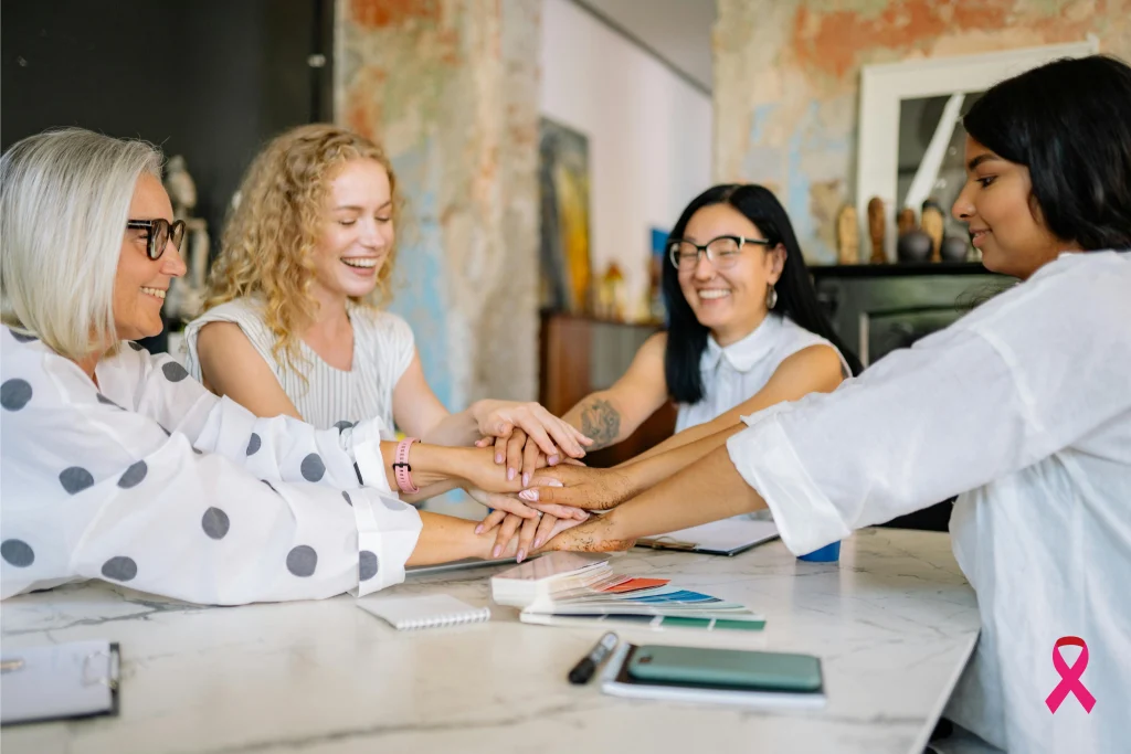 Groupe de femmes souriantes unies autour d’une table, symbolisant l’engagement collectif des entreprises pour la prévention de la santé des femmes pendant Octobre Rose.