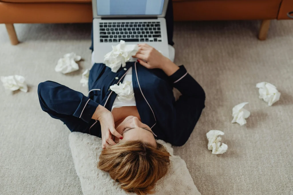 femme qui travaille avec des papiers éparpillés autour d'elle illustrant la charge mentale des femmes au travail